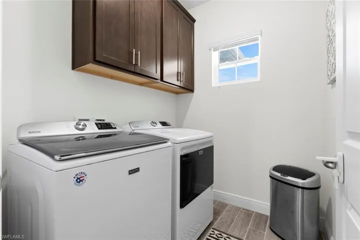 Laundry room with washer and clothes dryer, light hardwood / wood-style flooring, and cabinets