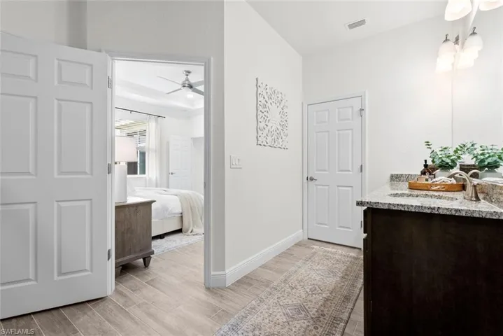 Bathroom with ceiling fan, a raised ceiling, vanity, and hardwood / wood-style flooring
