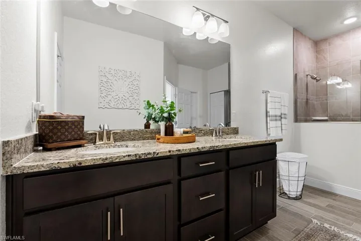 Bathroom featuring dual bowl vanity and tiled shower