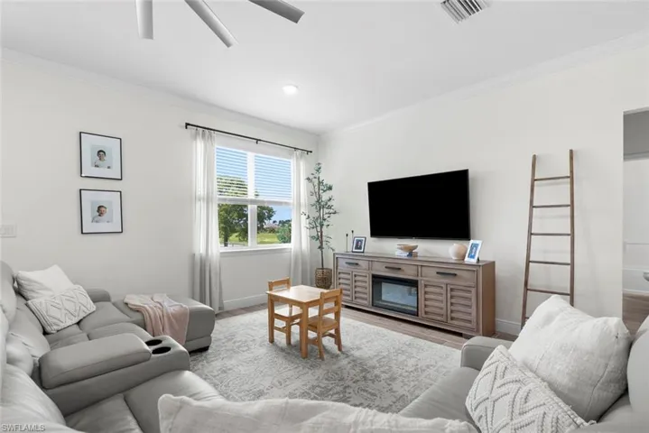 Living room featuring hardwood / wood-style floors, crown molding, and ceiling fan