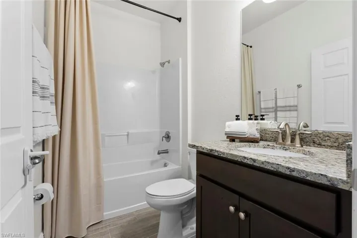 Full bathroom with toilet, vanity, and shower / bath combination with curtain