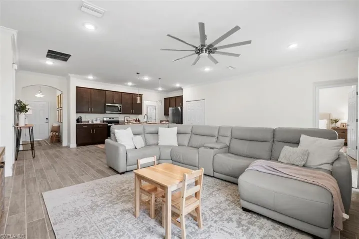 Living room with light hardwood / wood-style flooring, ornamental molding, sink, and ceiling fan