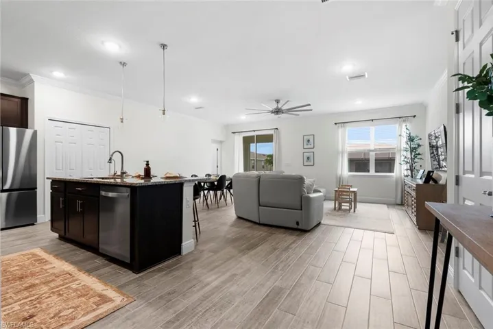 Kitchen with appliances with stainless steel finishes, an island with sink, ceiling fan, sink, and dark brown cabinetry