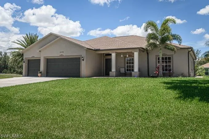 Ranch-style home featuring a front lawn and a garage
