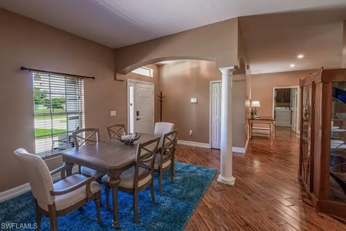 Dining space with decorative columns and hardwood / wood-style flooring