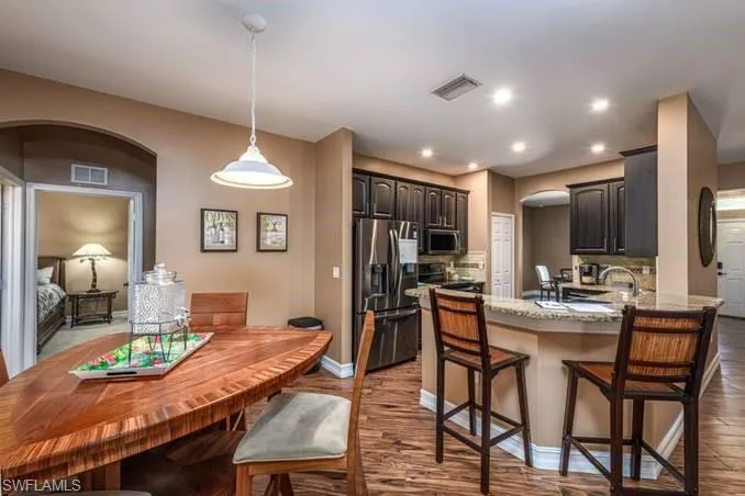 Kitchen with sink, appliances with stainless steel finishes, dark brown cabinets, light hardwood / wood-style floors, and kitchen peninsula