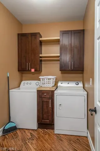 Laundry area with cabinets, wood-type flooring, and separate washer and dryer