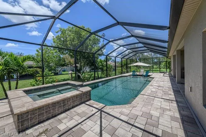 View of pool featuring an in ground hot tub, glass enclosure, and a patio area