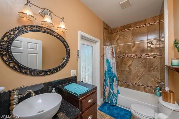 Full bathroom with shower / bath combo, toilet, and sink