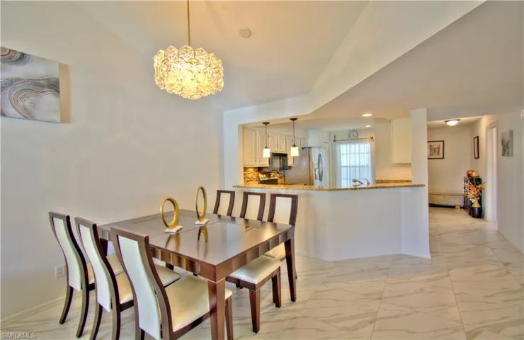 Dining space with light marble finish floors, hanging lights, and vaulted ceiling