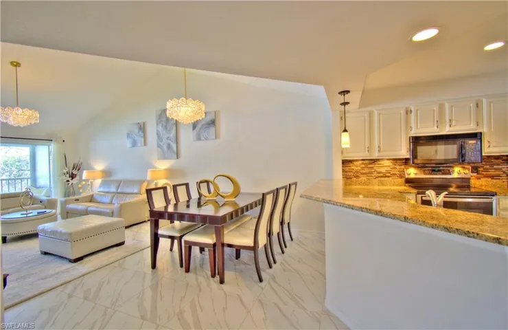 Dining room featuring hanging lights, light marble finish floors, and lofted ceiling