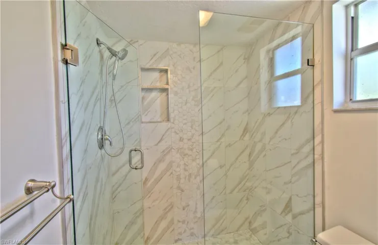 Bathroom with a marble finish shower and toilet