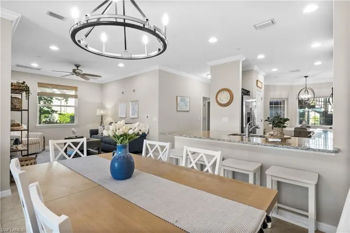 Tiled dining space featuring ceiling fan with notable chandelier, sink, and crown molding