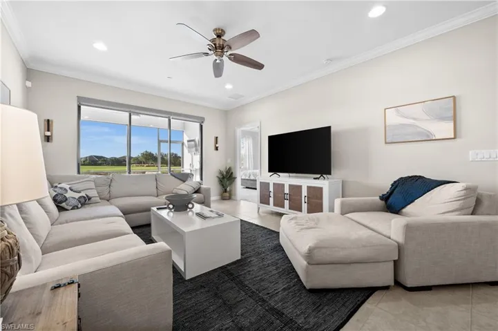 Living room featuring ceiling fan, crown molding, and light tile patterned flooring