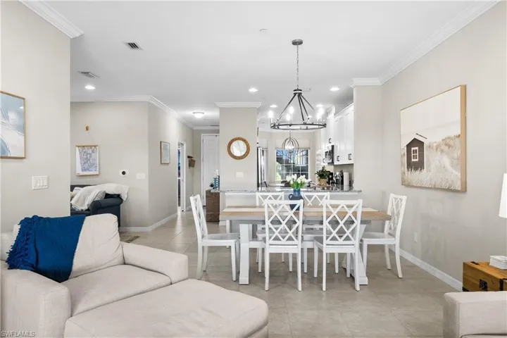 Tiled dining room with crown molding and an inviting chandelier
