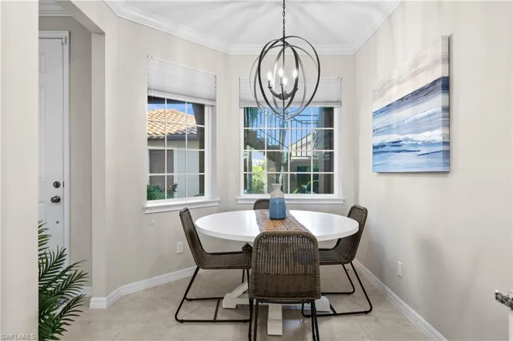 Tiled dining room featuring crown molding, a healthy amount of sunlight, and a notable chandelier
