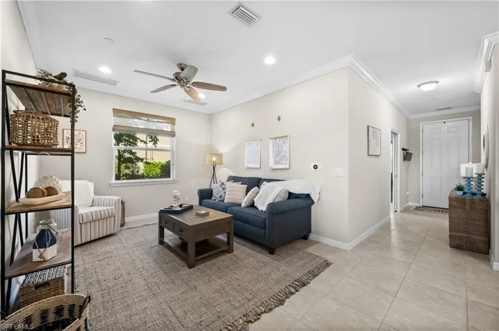 Living room featuring ceiling fan, light tile patterned flooring, and crown molding