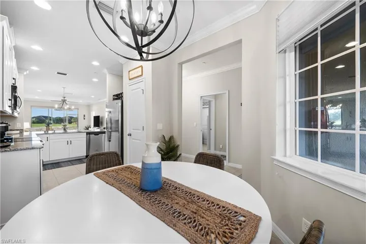 Dining area with sink, light tile patterned flooring, a chandelier, and ornamental molding