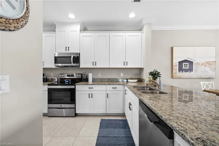 Kitchen with white cabinetry, ornamental molding, and appliances with stainless steel finishes
