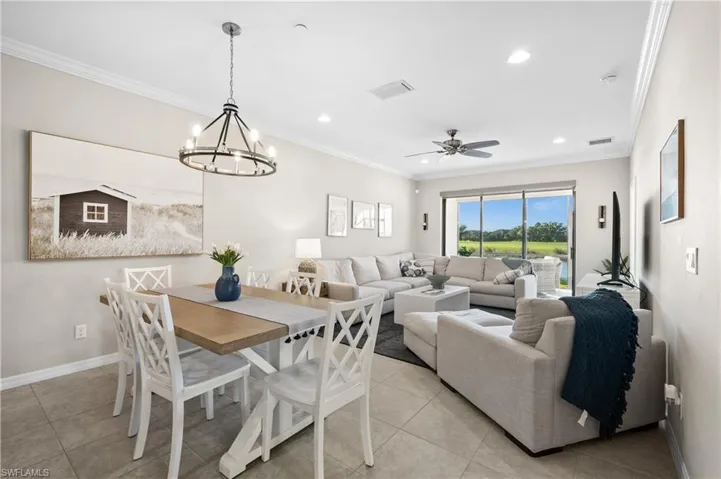 Dining area featuring crown molding, light tile patterned floors, and ceiling fan with notable chandelier