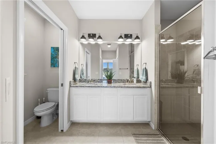 Bathroom with tile patterned flooring, vanity, toilet, and walk in shower