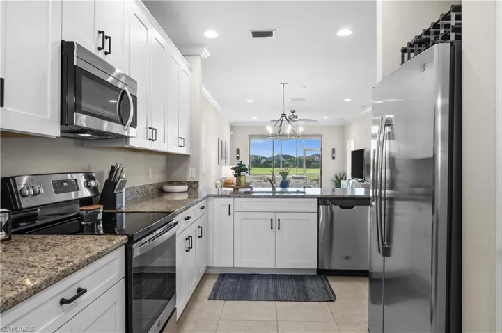 Kitchen featuring white cabinetry, sink, stainless steel appliances, crown molding, and stone countertops