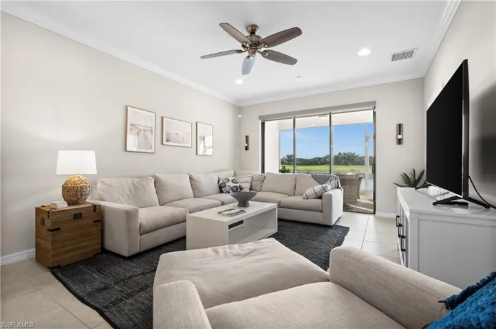 Living room featuring ceiling fan, light tile patterned floors, and ornamental molding