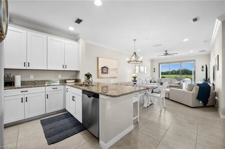 Kitchen featuring kitchen peninsula, white cabinets, ceiling fan with notable chandelier, stone counters, and dishwasher