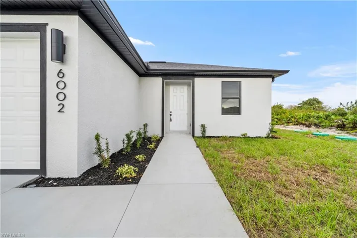 View of exterior entry featuring stucco siding and a lawn