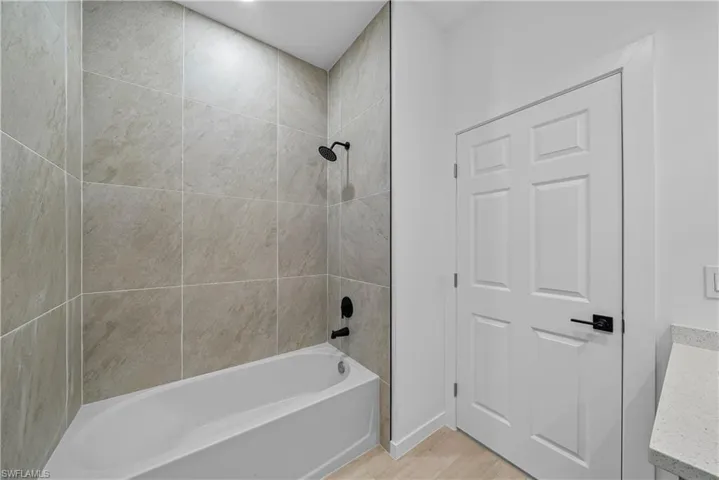 Bathroom with vanity, shower / bathtub combination, and light wood finished floors