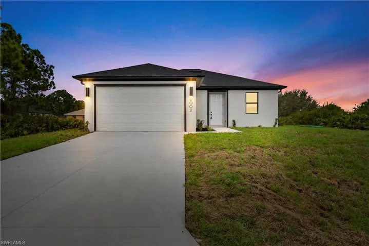 View of front of property featuring a lawn, a garage, concrete driveway, and stucco siding