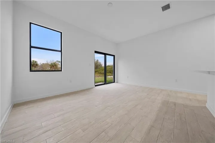 Spare room featuring light wood finished floors and a high ceiling