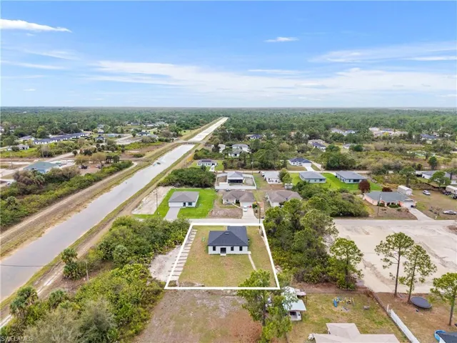 Aerial perspective of suburban area featuring property parcel outlined and a heavily wooded area