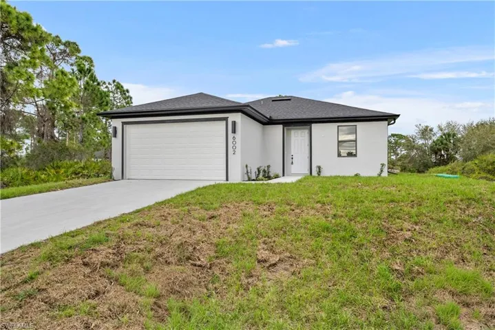 View of front facade with an attached garage, concrete driveway, a front yard, and stucco siding