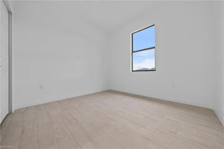 Unfurnished room featuring light wood finished floors and baseboards