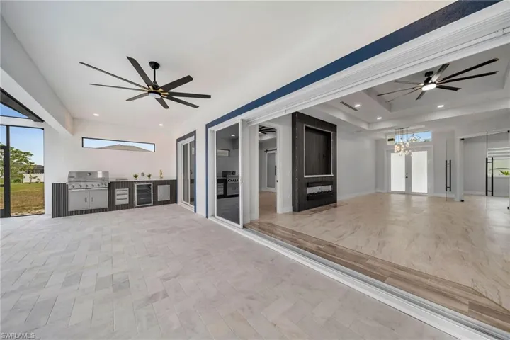 View of patio with an outdoor kitchen, ceiling fan, grilling area, and wine cooler