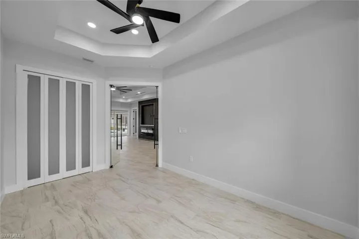 Unfurnished room with baseboards, a ceiling fan, visible vents, and a raised ceiling