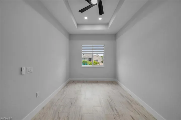 Spare room featuring baseboards, a ceiling fan, a tray ceiling, and recessed lighting