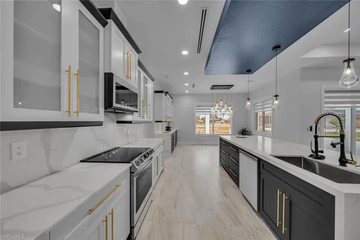 Kitchen featuring marble finish floor, a sink, pendant lighting, glass insert cabinets, and appliances with stainless steel finishes