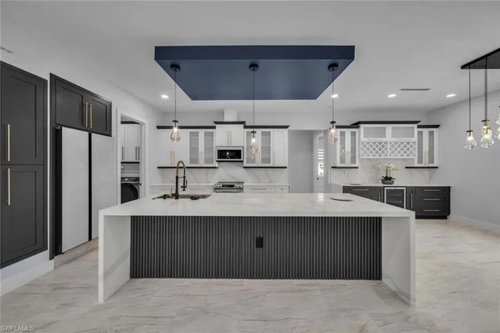 Kitchen with marble finish floor, white cabinets, appliances with stainless steel finishes, and a sink