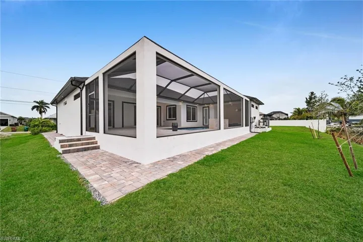 Rear view of house with glass enclosure, a lawn, a patio, and stucco siding