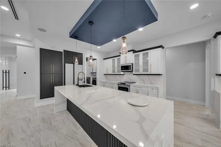 Kitchen with baseboards, light stone counters, stainless steel appliances, and a sink