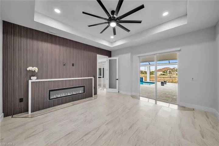 Unfurnished living room featuring recessed lighting, a raised ceiling, a ceiling fan, and baseboards