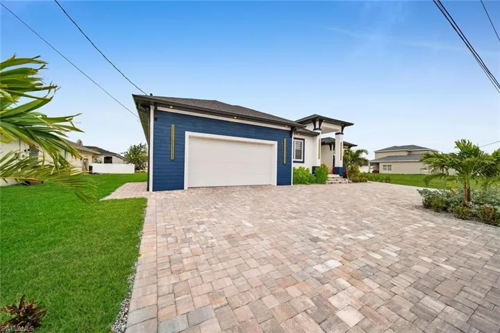 Prairie-style home with an attached garage, a front lawn, and decorative driveway