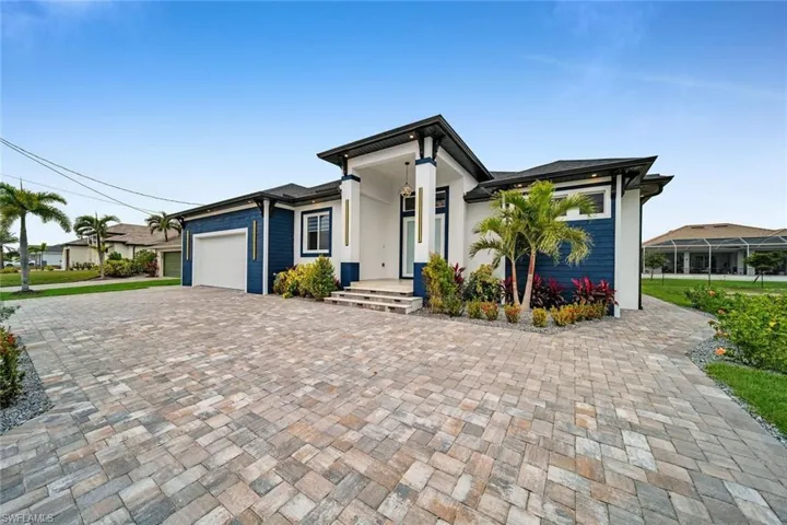 Prairie-style home with an attached garage, stucco siding, and decorative driveway