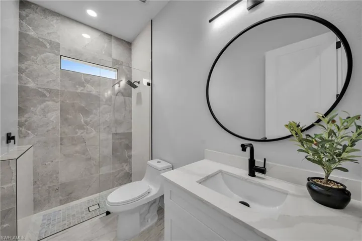 Bathroom with recessed lighting, walk in shower, toilet, and vanity