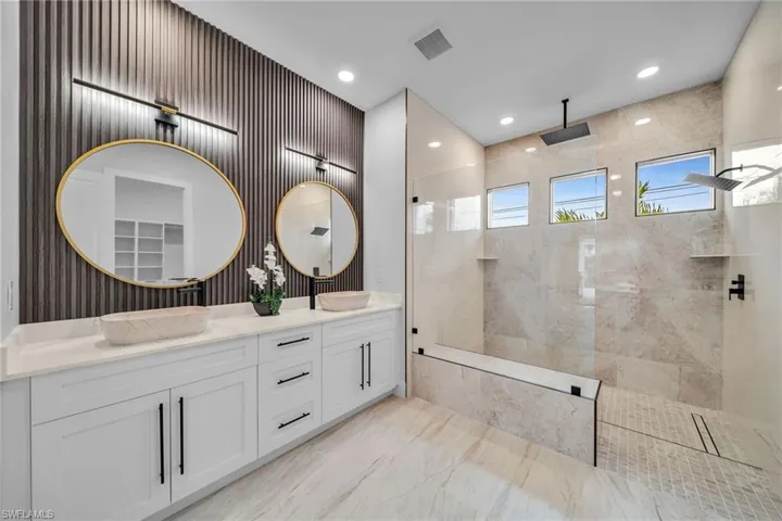 Full bath featuring marble finish floor, a sink, double vanity, and a walk in shower
