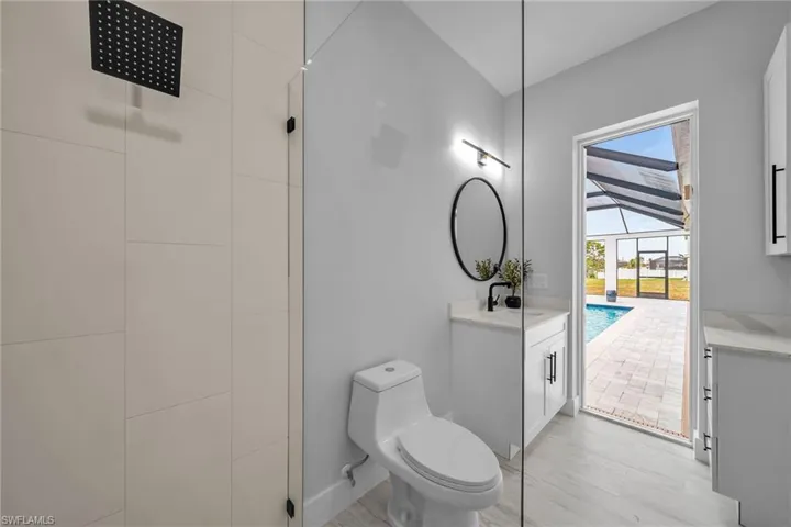 Bathroom featuring a tile shower, toilet, and vanity