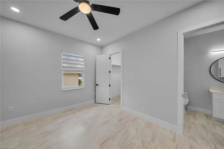 Unfurnished bedroom with a walk in closet, ensuite bath, ceiling fan, baseboards, and recessed lighting