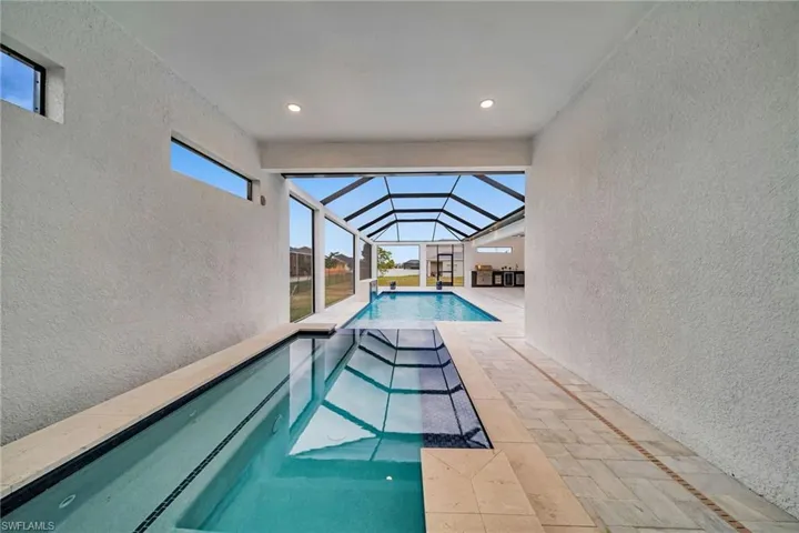 View of pool with a pool, glass enclosure, and a patio area